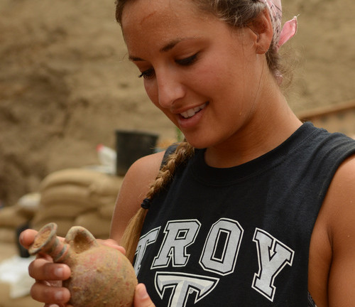Una estudiante examina una vasija de los siglos noveno a décimo, antes de esta era, que fue hallada cementerio. Foto de Melissa Aja/Expedición Leon Levy.